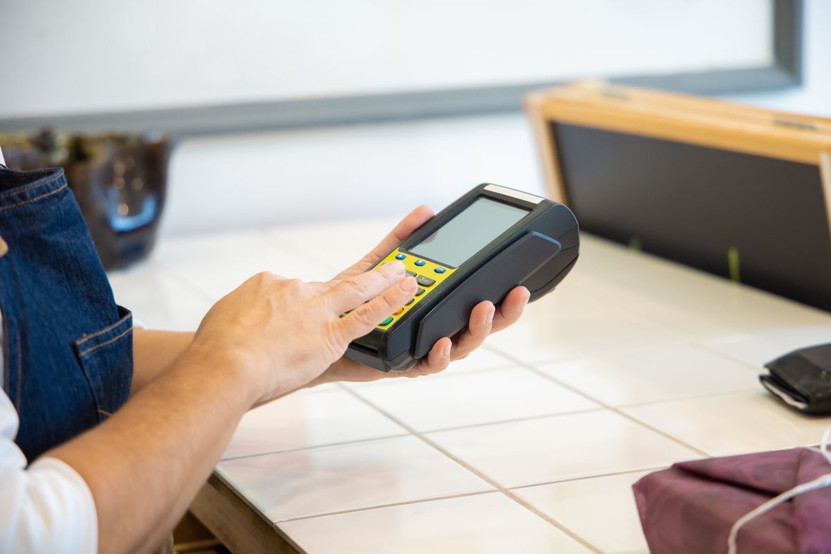 Close-up of a pair of hands using a card payment machine at a shop till point